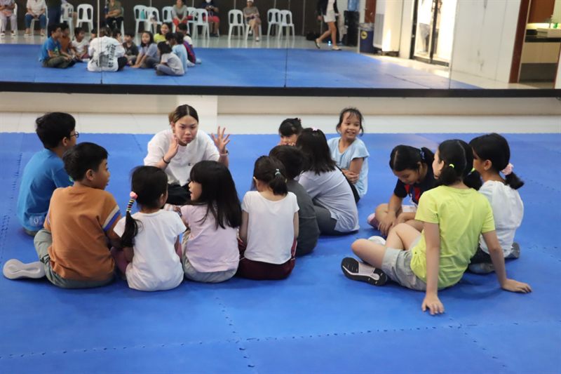 Children in a circle with a coach at a sports clinic