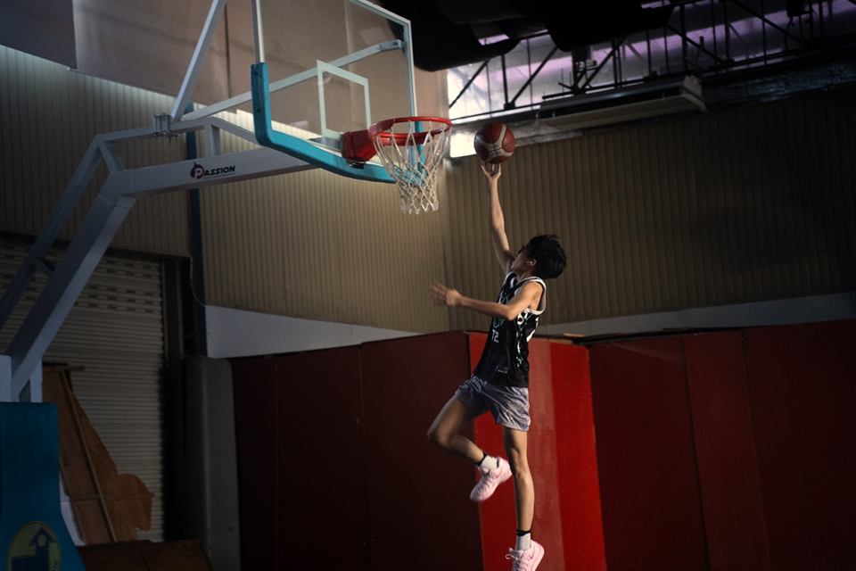 A young player rising to the hoop at a covered court