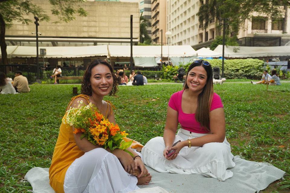 Two friends with flowers on a picnic blanket in the park