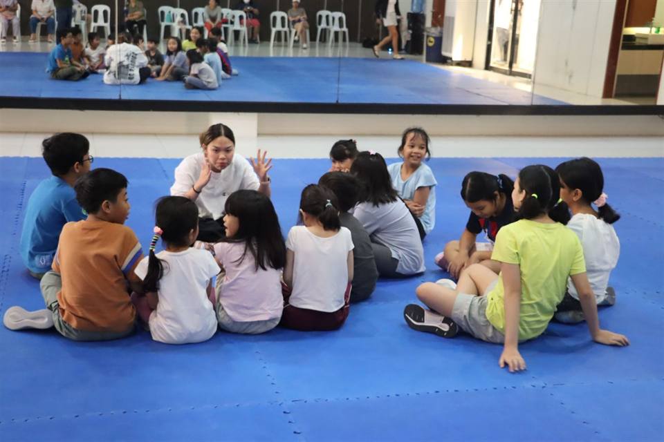 Children in a circle with a coach at a sports clinic