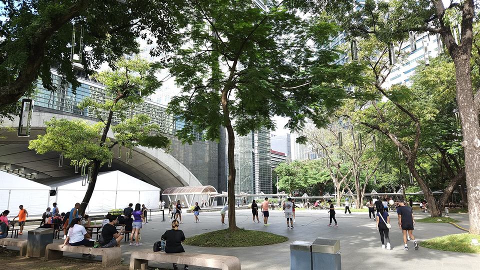 Ayala Triangle Gardens: lawns and trees, with office towers behind